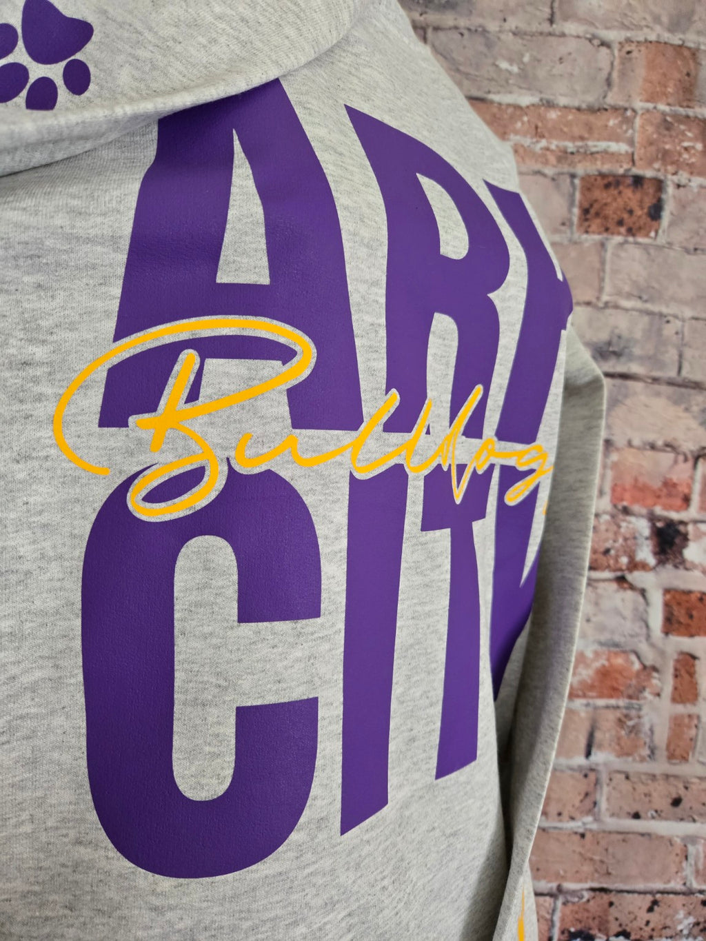 Close-up of purple Ark City Bulldogs varsity design on a heather gray crewneck