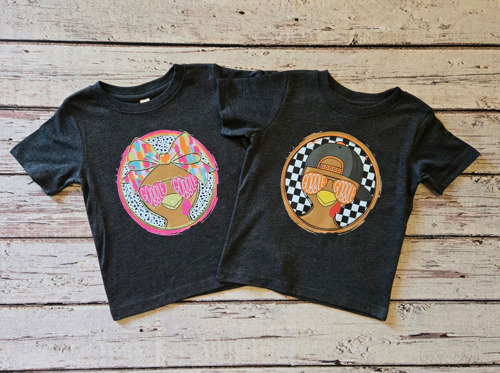 Two dark heather toddler short sleeve tees with girl and boy Gobble Gobble turkey designs